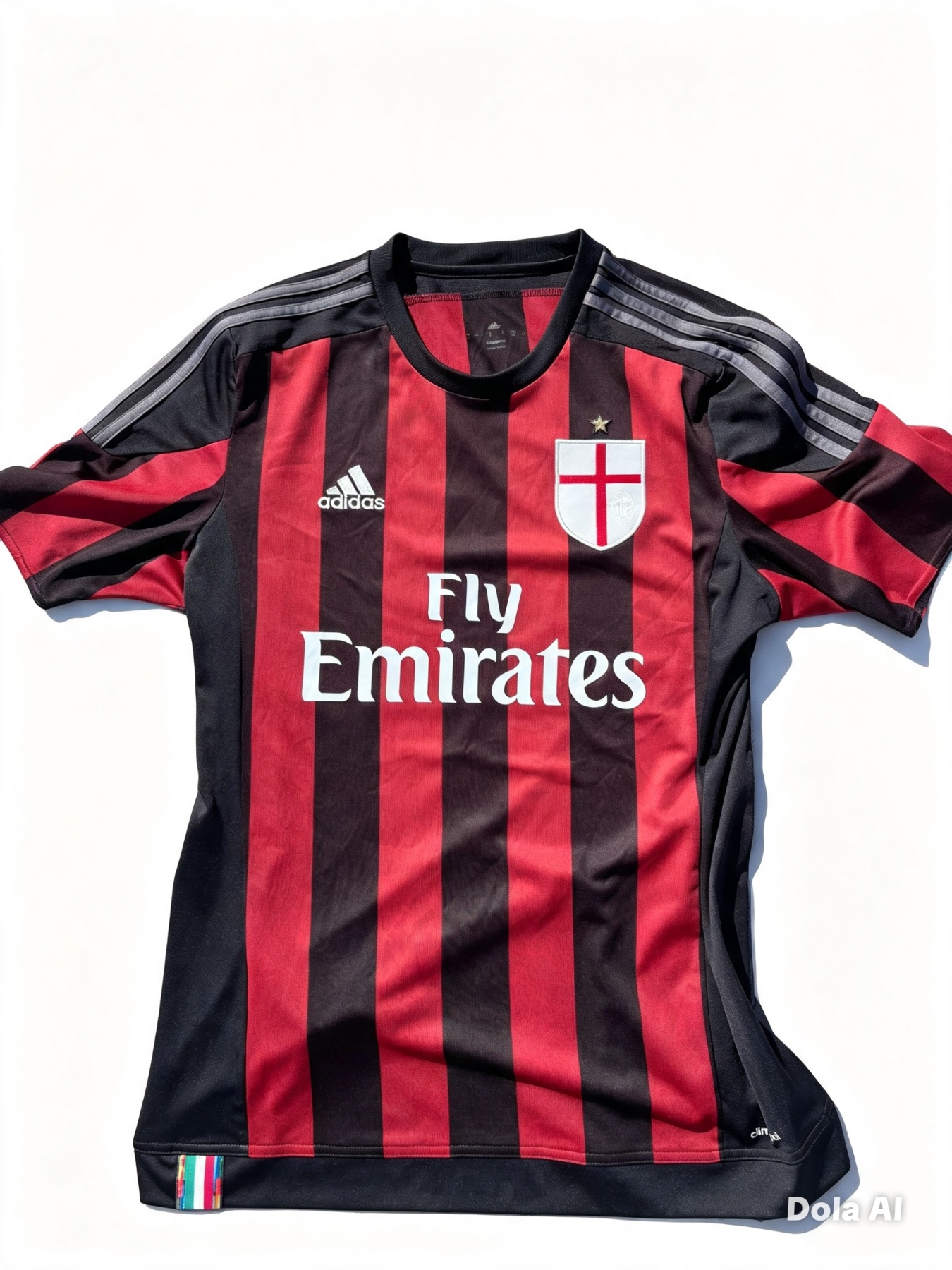 Front of an AC Milan 2015/16 home football shirt with red and black stripes. Features the Adidas logo, Fly Emirates sponsor, and a white St George cross shield crest